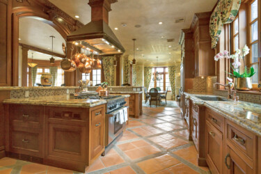 Photo of a kitchen with wood cabinets and terracotta flooring.