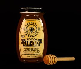 Photo of a jar of honey and a honey dipper.